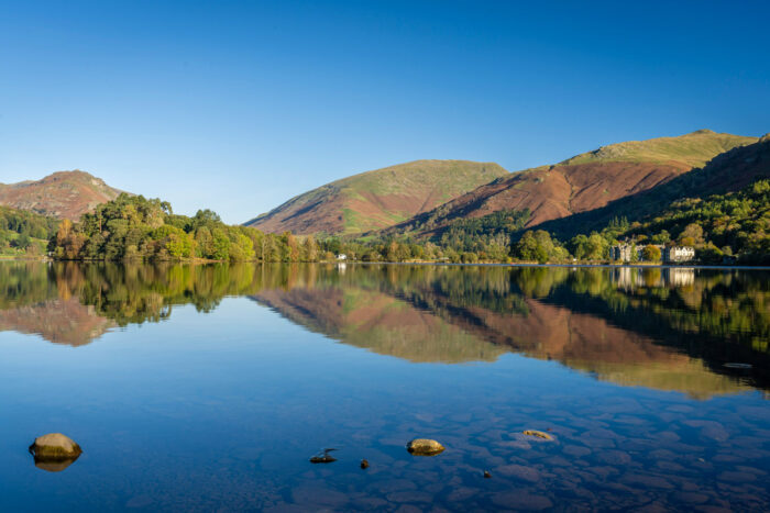 a large body of water surrounded by mountains and blue sky photo
