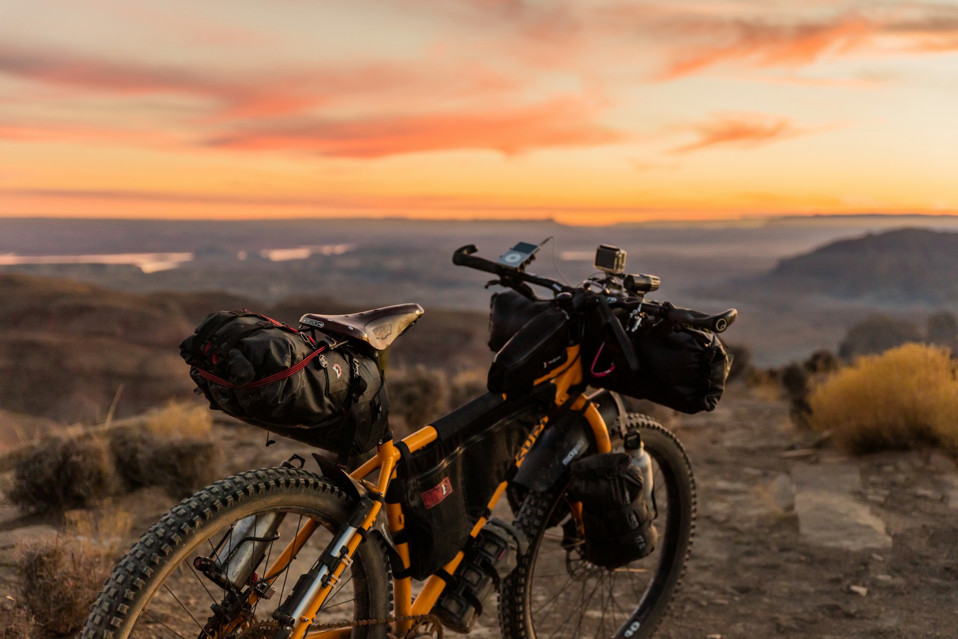 orange and black off-road bicycle on a hill at sunset