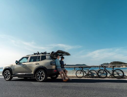 Grey SUV vehicle parked on a coastal road with father and son and bicycles