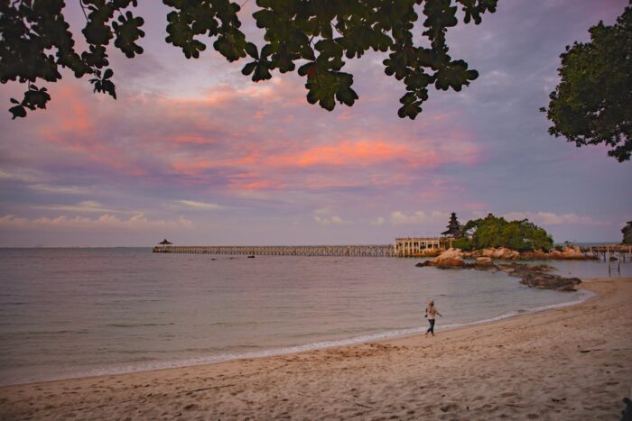 woman walking on a beach at sunset on an island in indonesia woman walking on a beach at sunset on an island in indonesia