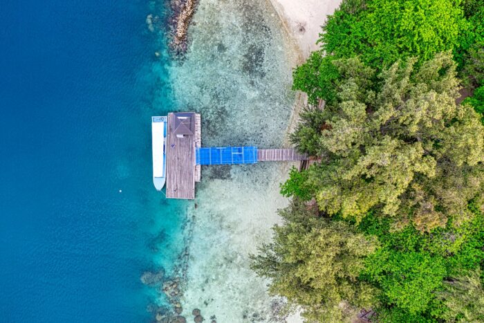 drone photo of boat, wooden dock and sea water on island in indonesia drone photo of boat, wooden dock and sea water on island in indonesia