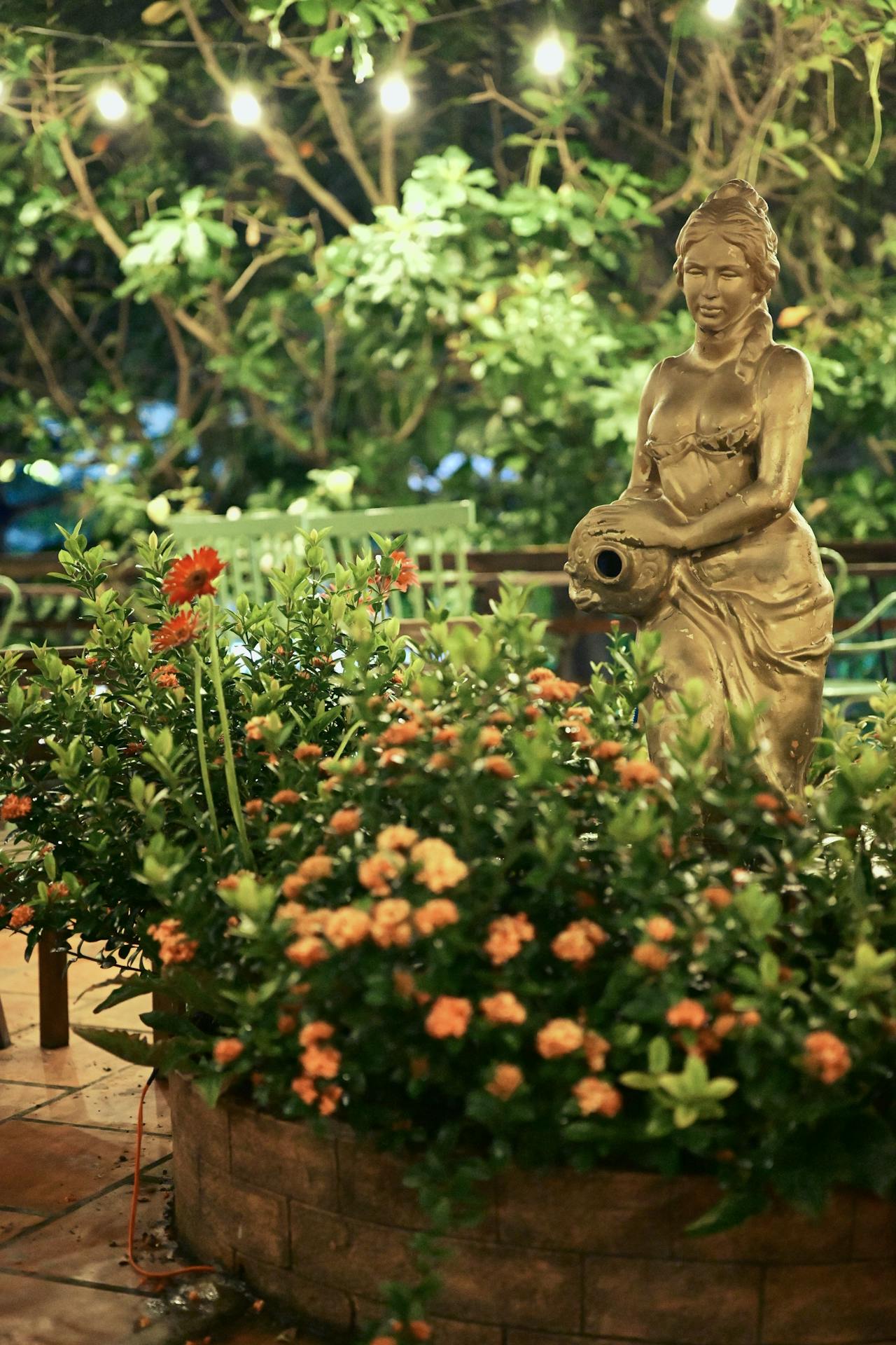 outdoor garden statue surrounded by lush foliage and flowers