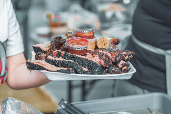 person holding paper tray with BBQ meat and sauce person holding paper tray with BBQ meat and sauce