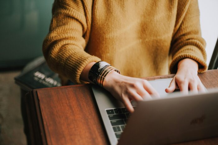 woman with yellow jumper using laptop computer