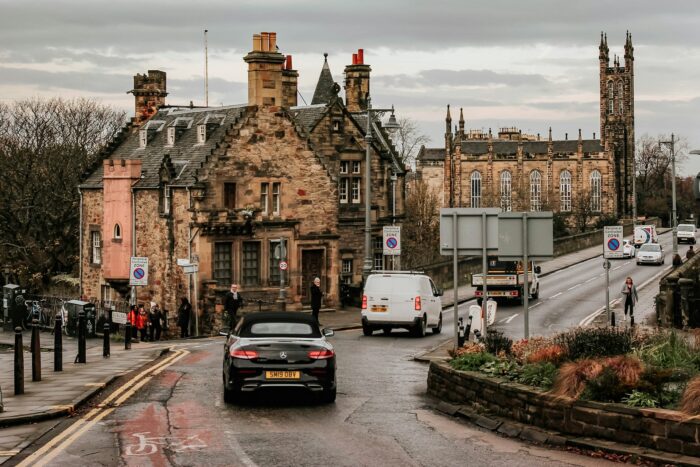 black car driving in front of old stone building in Edinburgh Scotland black car driving in front of old stone building in Edinburgh Scotland