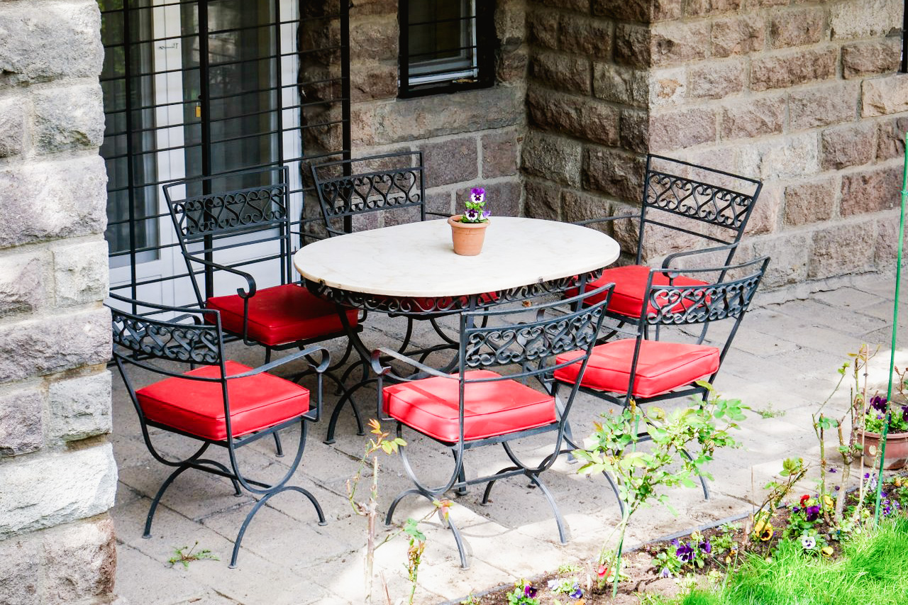 Cozy outdoor patio in Ankara with wrought iron furniture and vibrant red cushions, perfect for relaxation.