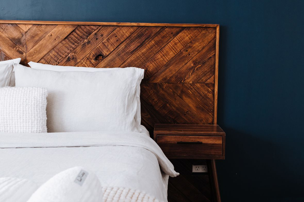 Modern bedroom showcasing dark blue wall, wooden headboard, and minimalist design
