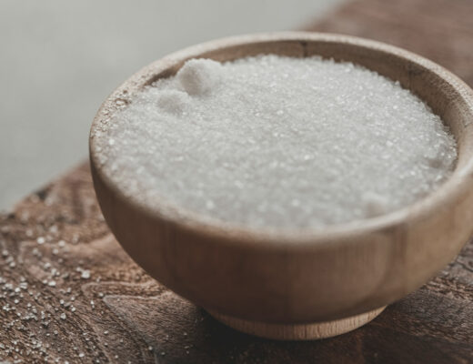 a wooden bowl of white sugar on a table