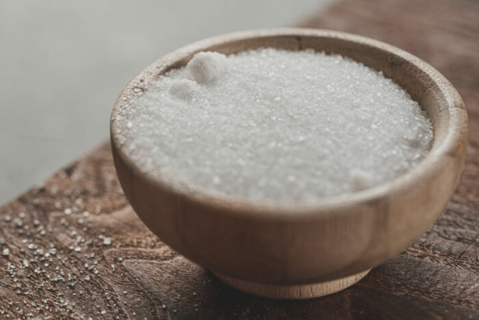 a wooden bowl of white sugar on a table a wooden bowl of white sugar on a table