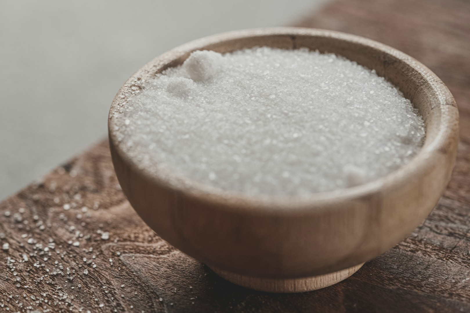 a wooden bowl of white sugar on a table
