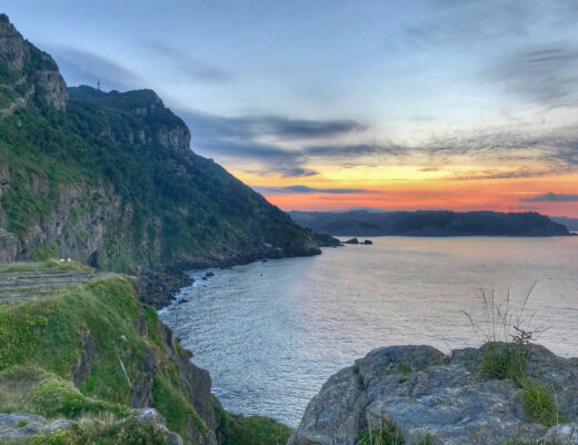 calm body of water under a cliff side at sunset in basque country spain