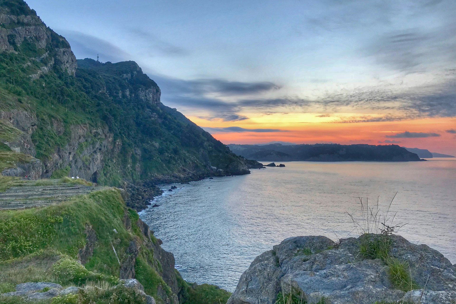 calm body of water under a cliff side at sunset in basque country spain