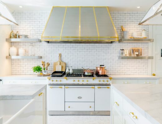 kitchen design with white cabinets with gold accents, large oven and stove hood