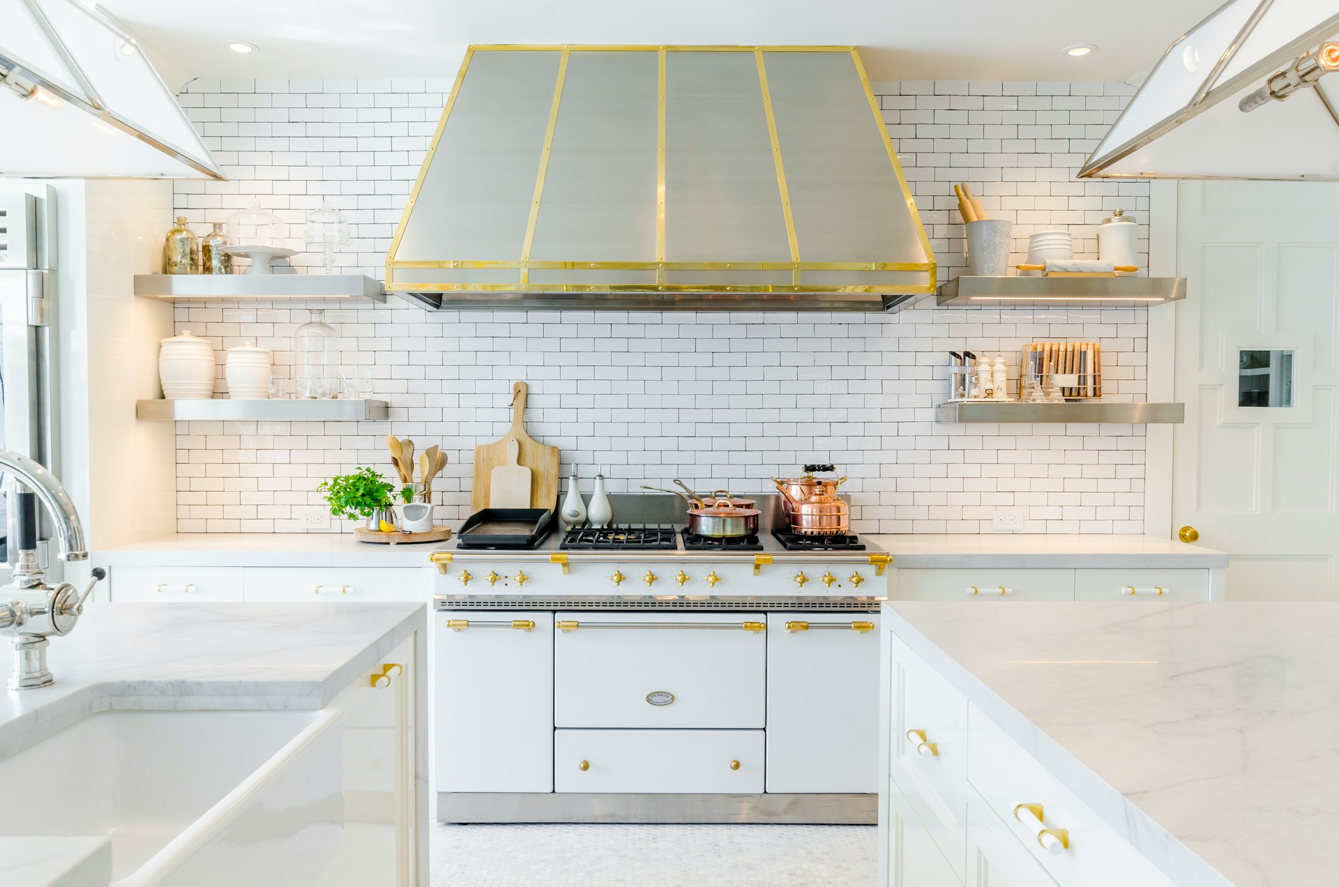 kitchen design with white cabinets with gold accents, large oven and stove hood