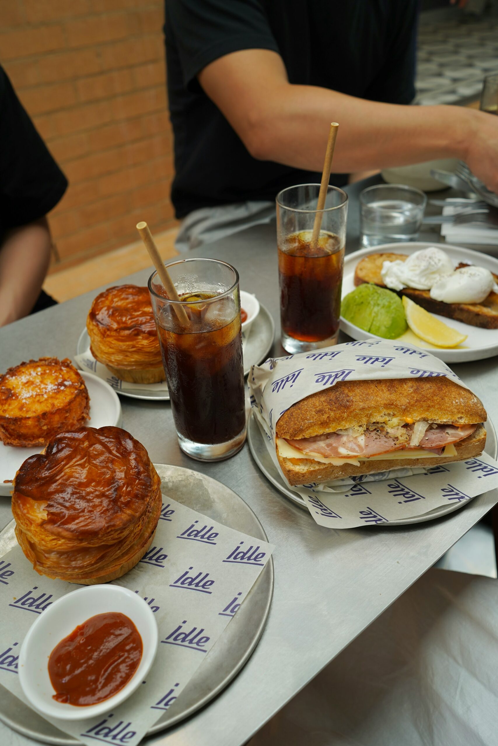 Autralian meat pie and sauce, a sandwich and iced black coffee on a table in a cafe Autralian meat pie and sauce, a sandwich and iced black coffee on a table in a cafe in Brisbane