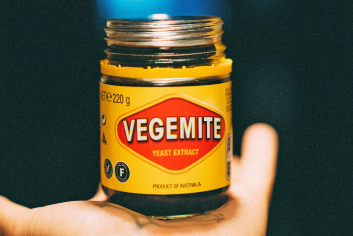 hand holding a yellow and dark vegemite glass jar hand holding a yellow and dark vegemite glass jar