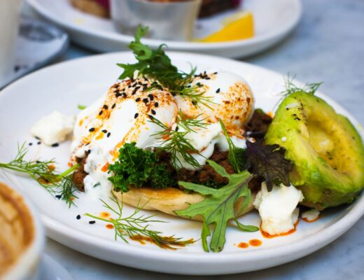 Delicious brunch featuring poached eggs, avocado, and herbs on a plate.