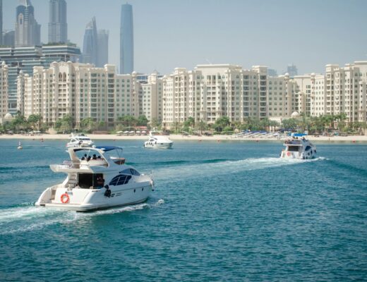 a group of boats in water in front of Dubai city skyline