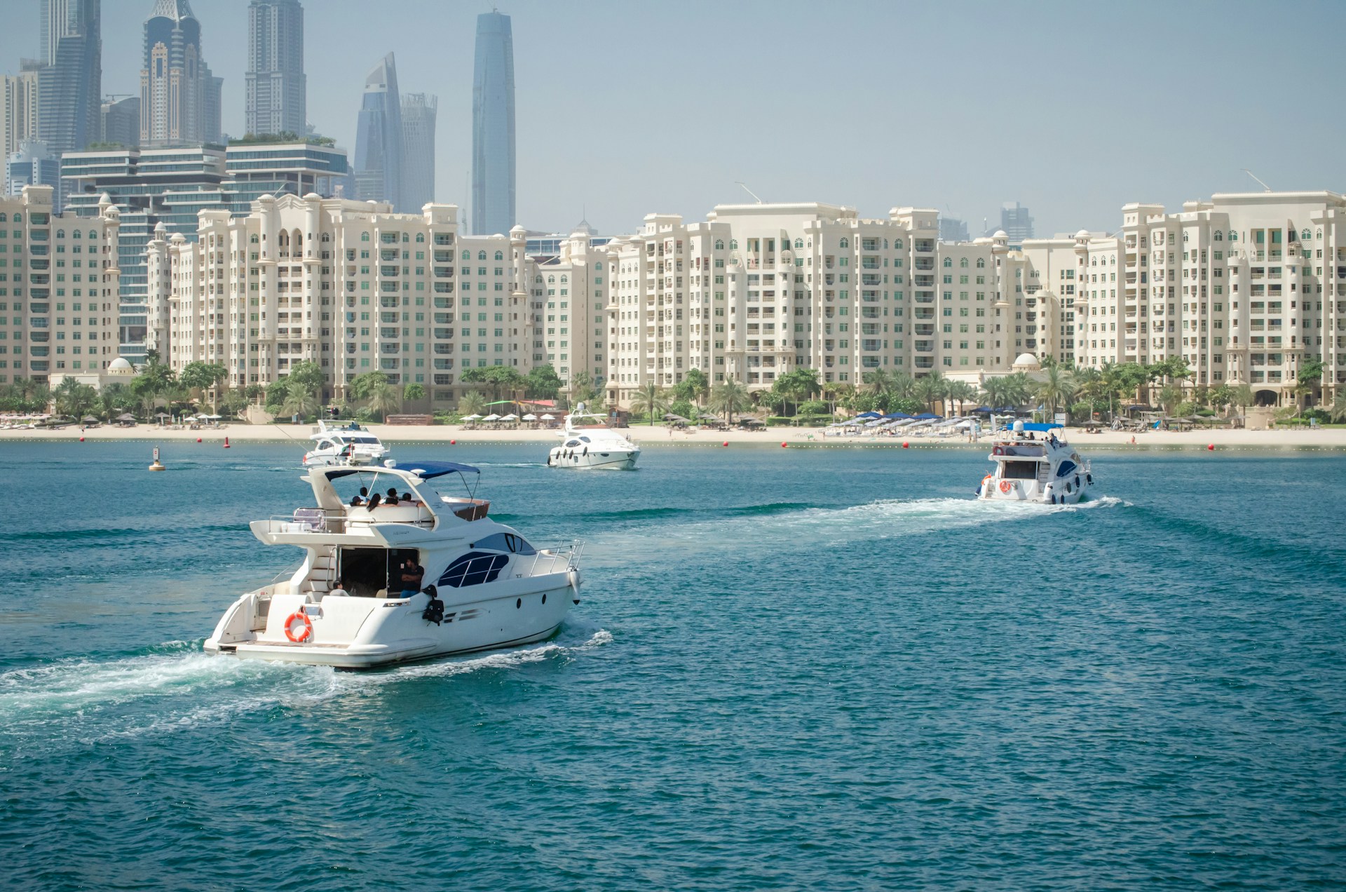 a group of boats in water in front of Dubai city skyline