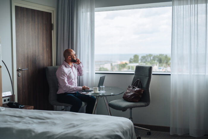 man working on a laptop computer in a hotel room overlooking the seaside man working on a laptop computer in a hotel room overlooking the seaside