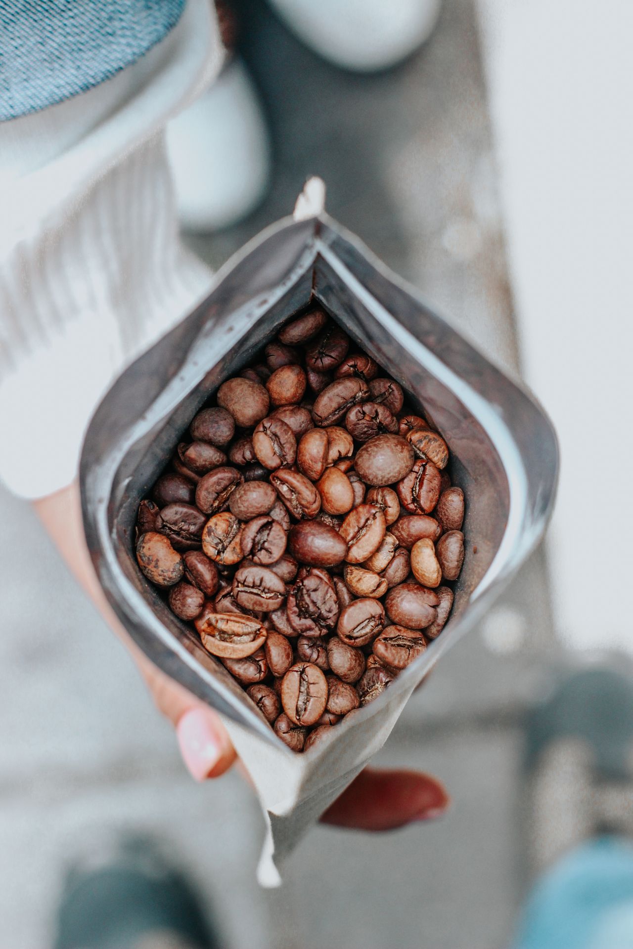 A closeup image of fresh coffee beans in a bag being held by a hand, offering a rich aroma experience. A closeup image of fresh coffee beans in a bag being held by a hand, offering a rich aroma experience.