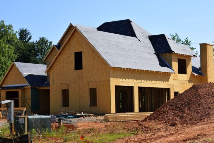 A partially built wooden house under construction, showcasing its progress and design in daylight. A partially built wooden house under construction, showcasing its progress and design in daylight.