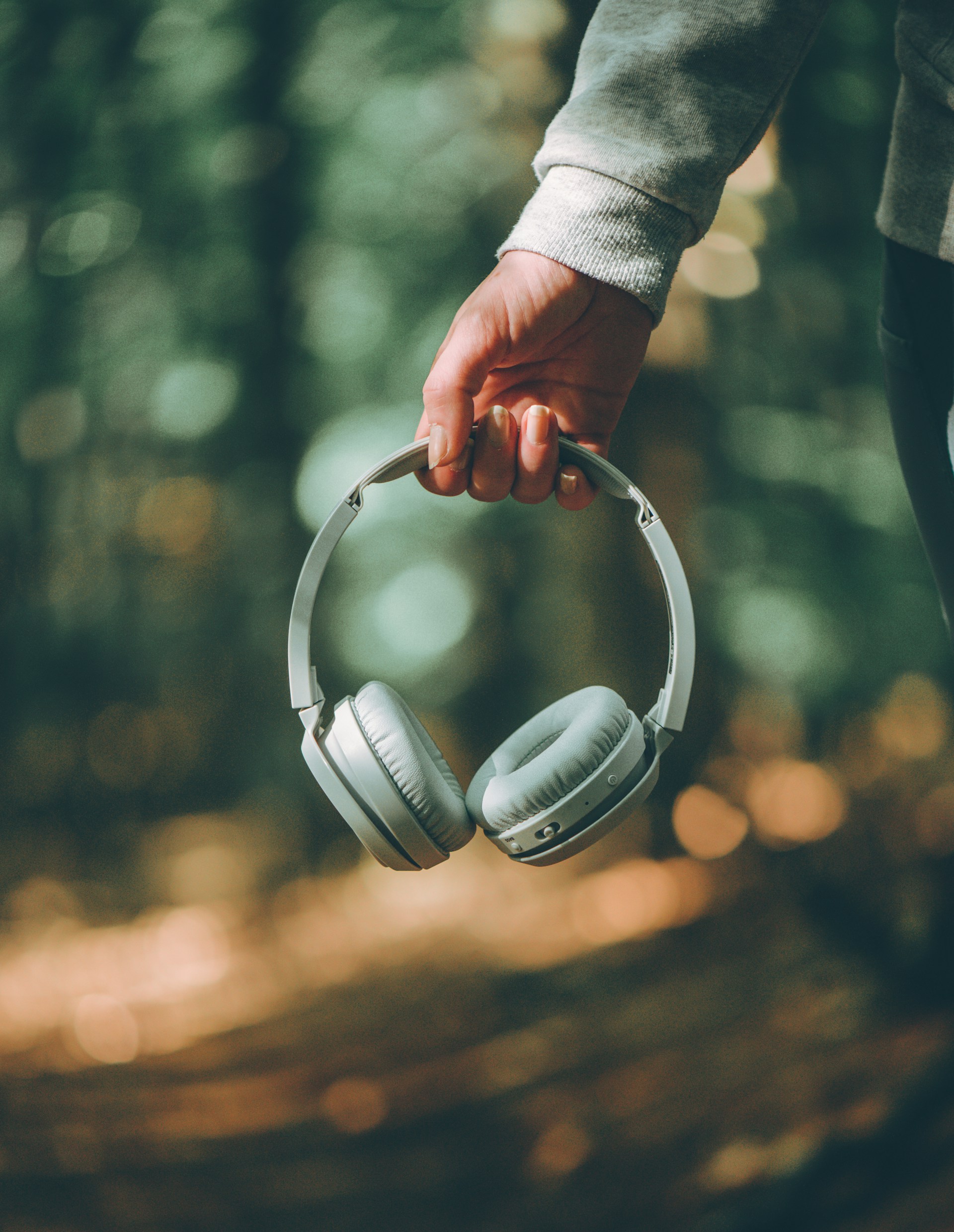 a person holding a pair of green headphones in their hand a person holding a pair of green headphones in their hand