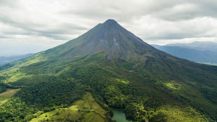 aerial view of the lush green Arenal Volcano in Costa Rica against a cloudy sky.